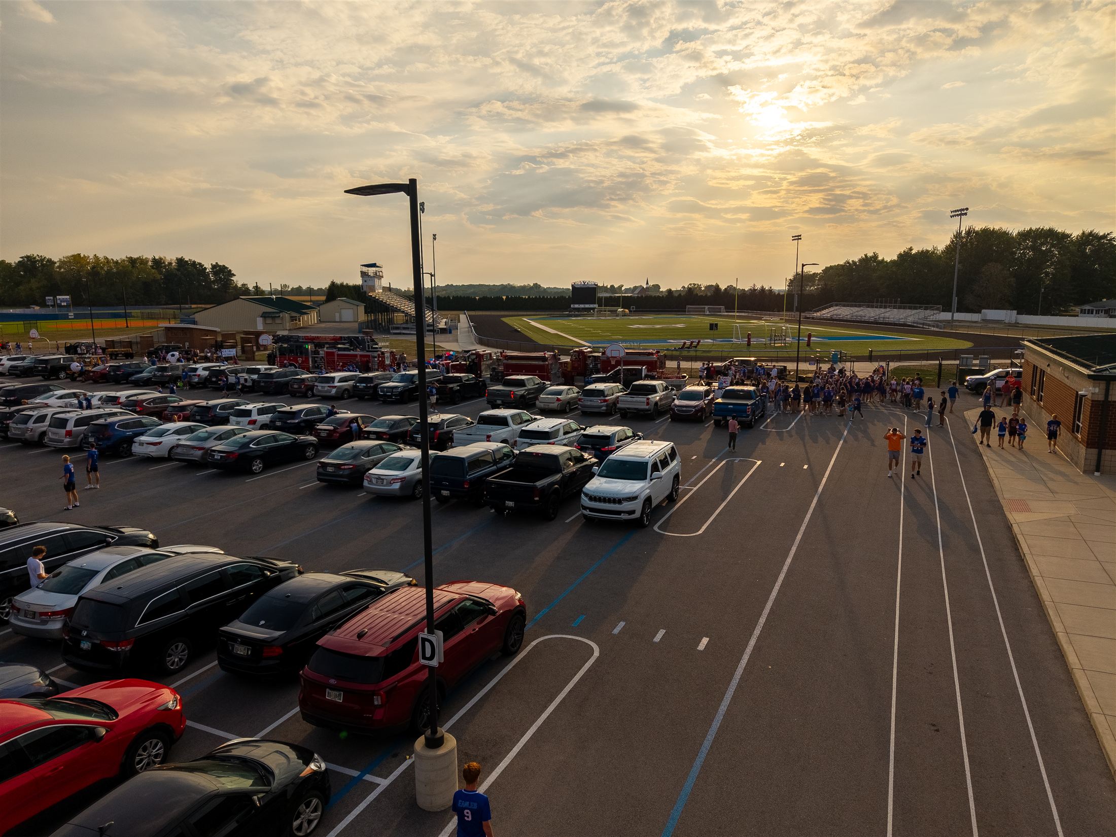 Friday night lights — LB stadium and packed parking lot at sunset